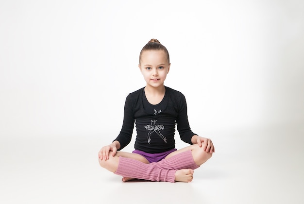 Jolie petite fille faisant de la gymnastique sur fond blanc