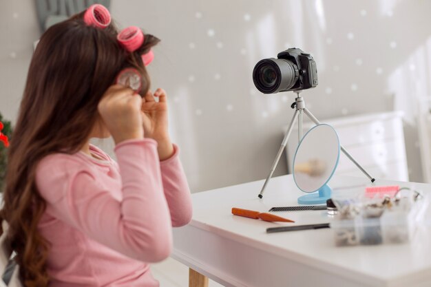 Jolie petite fille frisant une mèche de ses cheveux devant la caméra