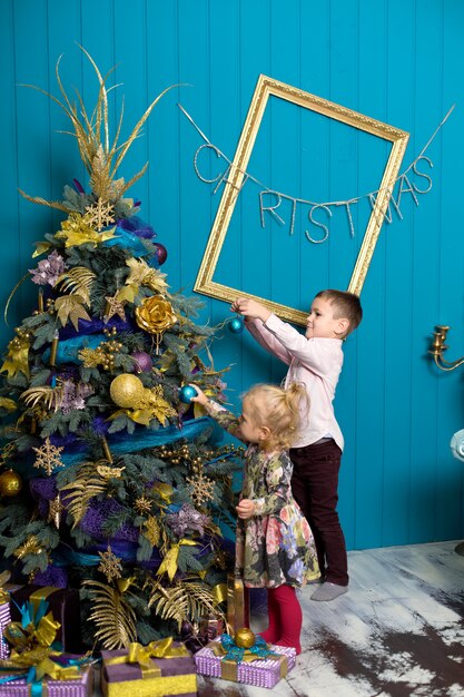 Jolie petite fille et garçon décorer un sapin de Noël. Frère et Soeur la veille de Noël