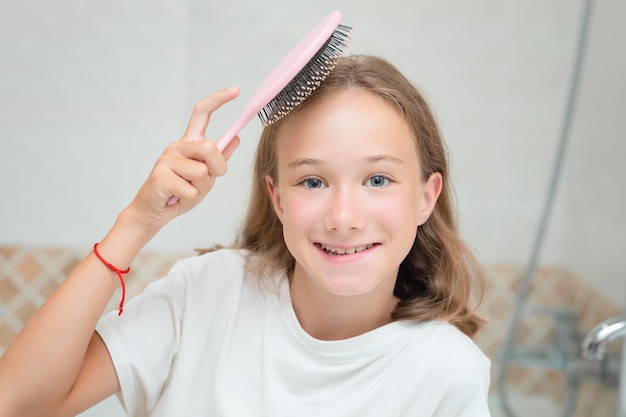 Une jolie petite fille avec de grands yeux bleus et un peigne dans sa main l'enfant peigne les cheveux indisciplinés mignon