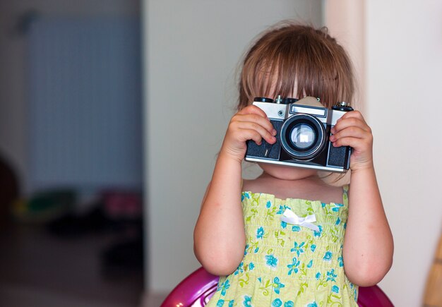 Jolie petite fille heureuse avec appareil photo vintage