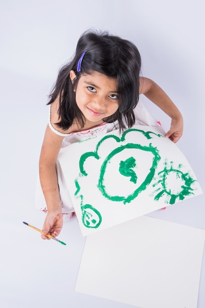 Jolie petite fille indienne ou asiatique appréciant la peinture à la maison avec du papier, de l'aquarelle et un pinceau d'art. Mise au point sélective