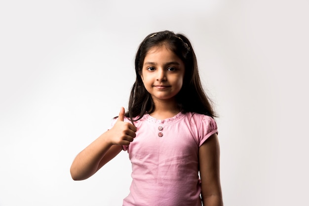 Jolie petite fille indienne ou asiatique montrant le pouce en l'air, debout isolée sur fond blanc