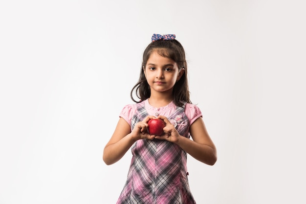 Jolie petite fille indienne ou asiatique tenant des pommes vertes et rouges - concept d'alimentation saine