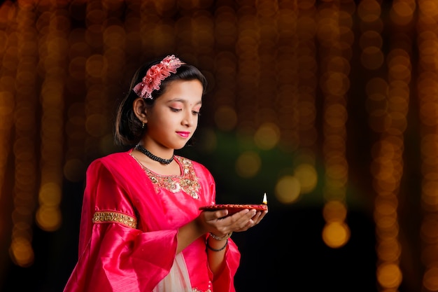 Jolie petite fille indienne tenant des lampes à huile ou diya pour la célébration de Diwali.