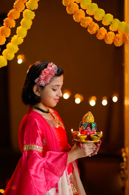 Jolie petite fille indienne tenant des lampes à huile ou diya pour la célébration de Diwali.