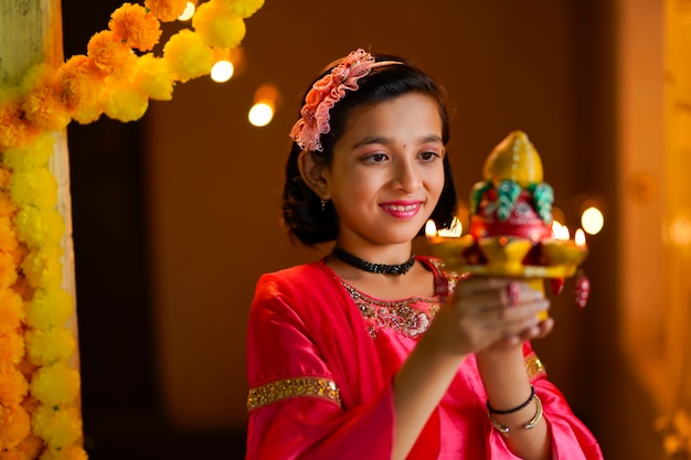 Jolie petite fille indienne tenant des lampes à huile ou diya pour la célébration de Diwali.