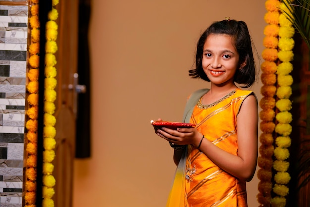 Jolie petite fille indienne tenant des lampes à huile ou diya pour la célébration de Diwali.