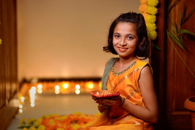 Jolie petite fille indienne tenant des lampes à huile ou diya pour la célébration de Diwali.