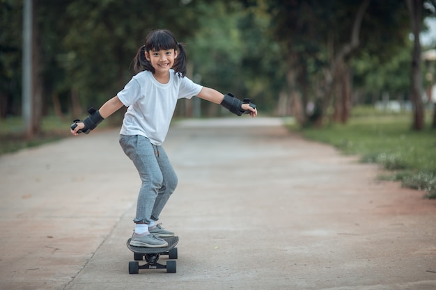 Jolie petite fille jouant au skateboard ou au surf skate dans le skate park