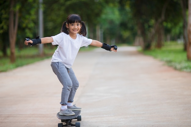 Jolie petite fille jouant au skateboard ou au surf skate dans le skate park