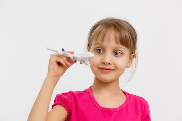 Jolie petite fille jouant avec un avion jouet. Isolé sur fond blanc