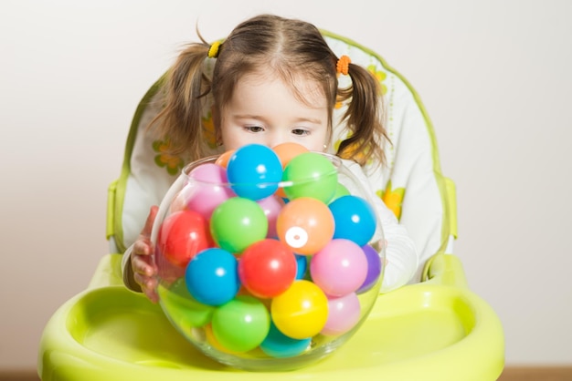 Jolie petite fille jouant avec des boules colorées à la table à la maison