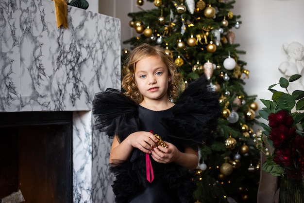 Jolie petite fille jouant avec un cadeau de Noël dans ses mains et des arbres de Noël avec des lumières Joyeux Noël et joyeuses fêtes