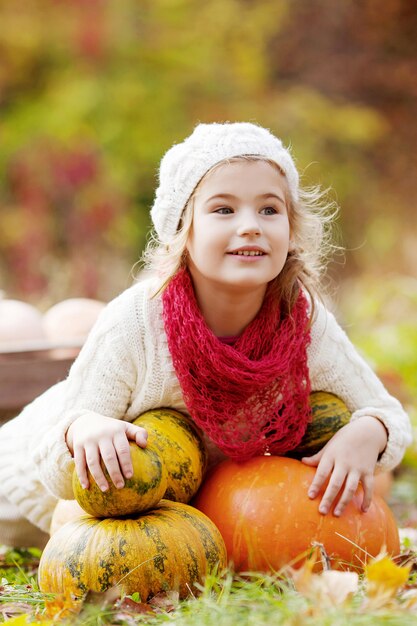 Jolie petite fille jouant avec des citrouilles en automne parc. Activités d'automne pour les enfants