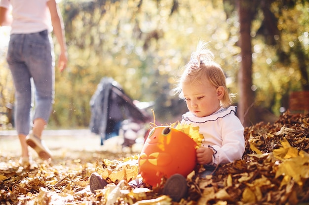 Jolie petite fille jouant dans les feuilles au parc d'automne avec ses parents.