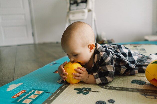 Jolie petite fille jouant avec une orange sur un tapis de jeu