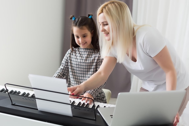 Jolie petite fille joue au piano, synthétiseur. Entraînement. Éducation. L'école. Formation esthétique. Classe élémentaire.