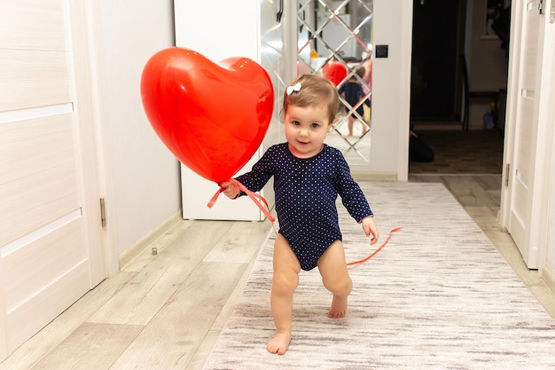 Une jolie petite fille joue avec une boule rouge en forme de coeur Belle carte postale cadeau
