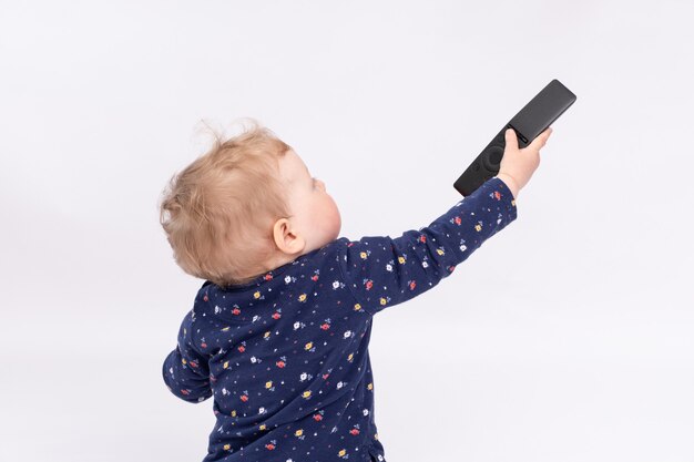 Jolie petite fille joue avec une télécommande sur fond blanc