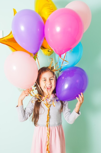 Jolie petite fille joyeuse à la fête d'anniversaire avec des ballons