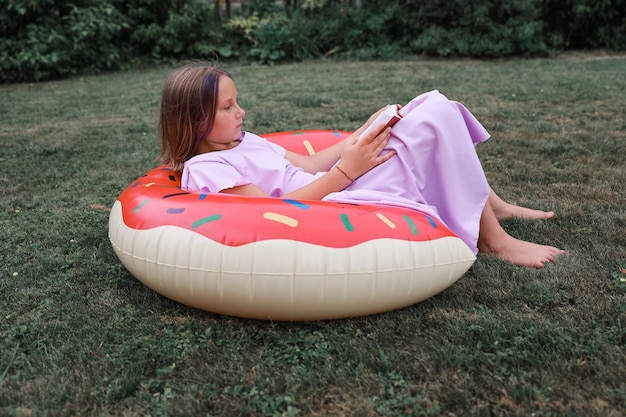 Photo jolie petite fille lisant un livre à l'extérieur. repos d'été