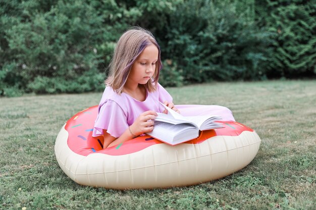 Jolie petite fille lisant un livre à l'extérieur. Repos d'été