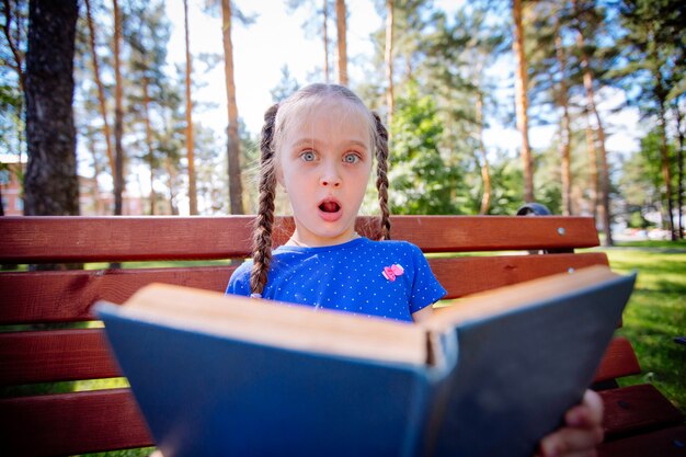 Jolie petite fille lit un livre à l'extérieur