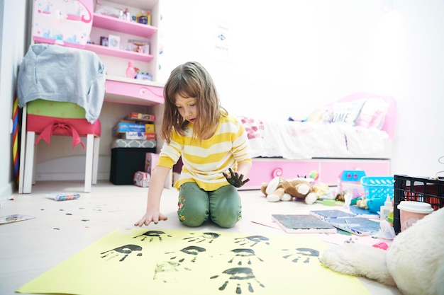 jolie petite fille à la maison peinture avec les mains drôle pas de sourire de dent