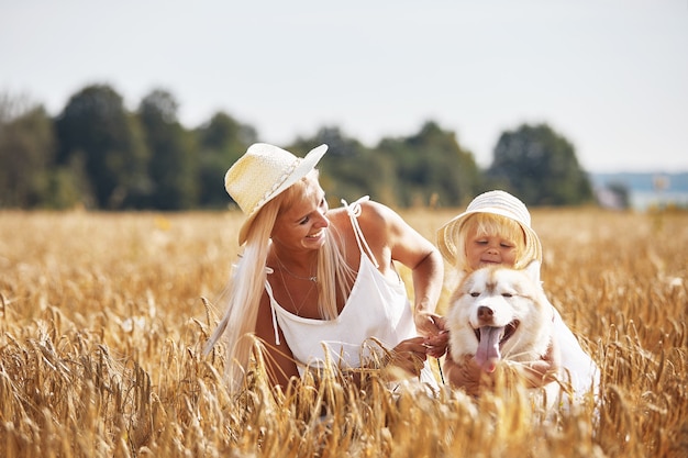 Jolie petite fille avec maman et chien sur champ de blé.