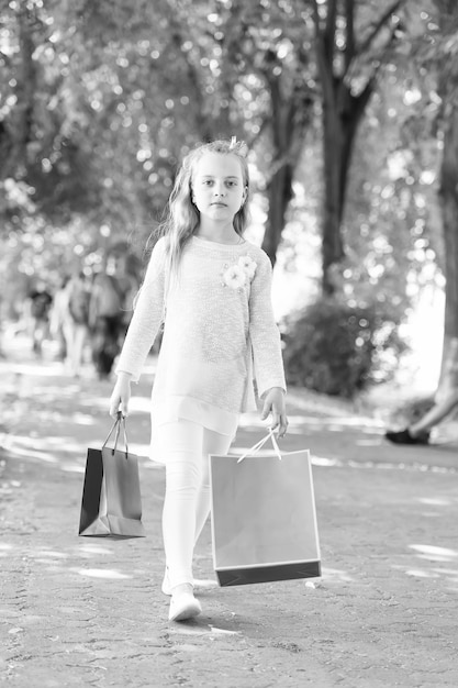 Jolie petite fille marchant avec les sacs à provisions roses