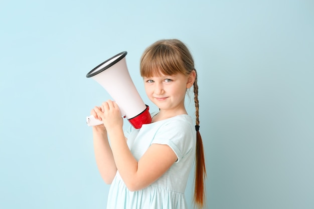 Jolie petite fille avec mégaphone sur la couleur