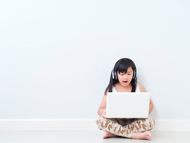 Jolie petite fille avec un ordinateur portable à la maison