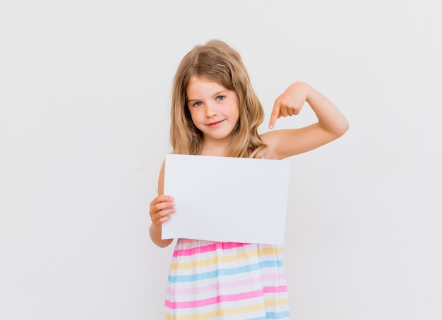 Jolie petite fille avec un papier vierge blanc.