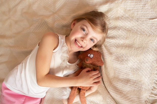 Photo jolie petite fille avec une peluche sur le canapé