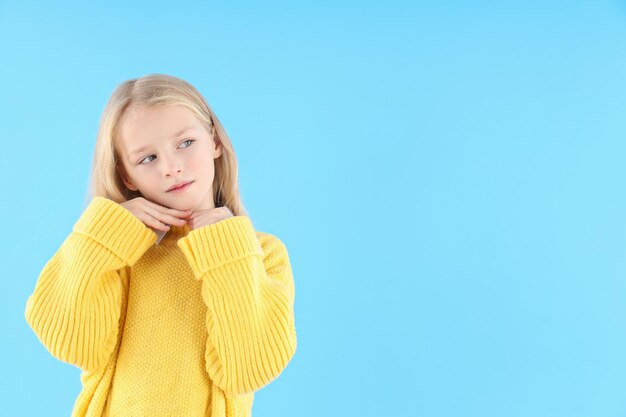 Jolie petite fille en pull sur fond bleu