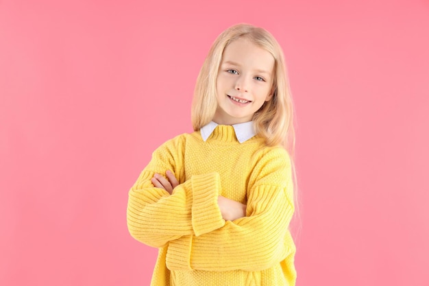 Jolie petite fille en pull sur fond rose