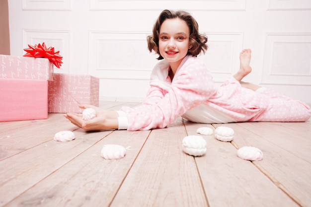 Jolie petite fille en pyjama avec des bonbons posés sur le sol