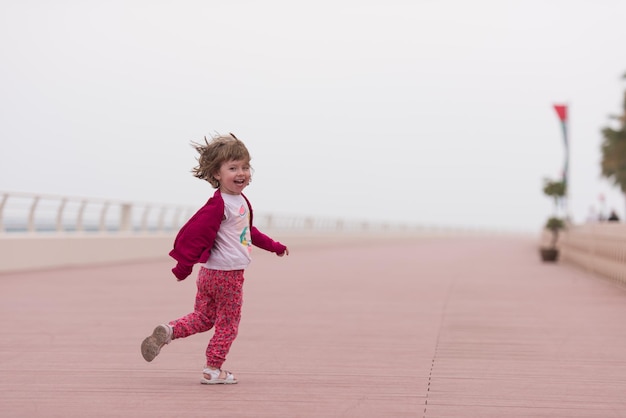 jolie petite fille qui court et passe joyeusement son temps sur la promenade au bord de la mer