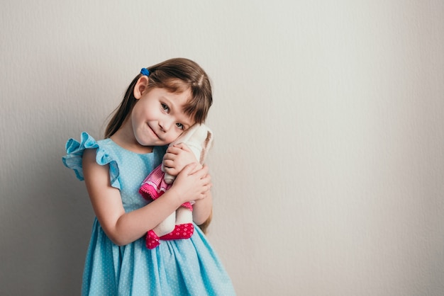 Jolie petite fille en robe bleue et détient son copyspace de lapin jouet