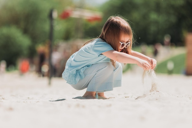 jolie petite fille en robe bleue payant sur la plage