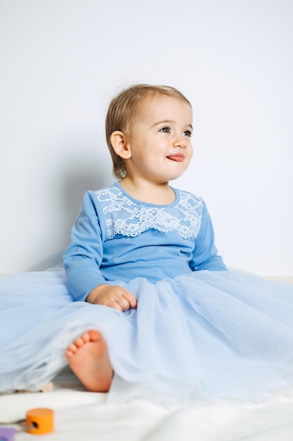 Jolie petite fille en robe de princesse bleue jouant avec des jouets à la maison Robes pour enfants pour les vacances de bal et d'anniversaire