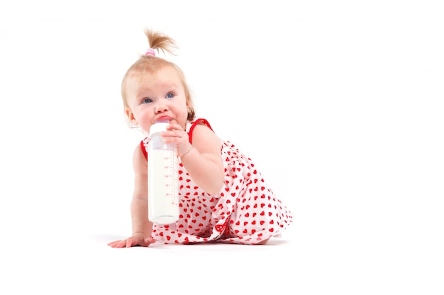 Jolie petite fille en robe rouge avec une bouteille de lait