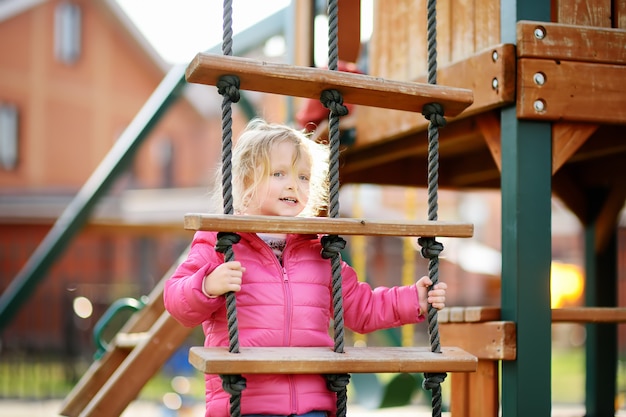 Jolie petite fille s&#39;amusant sur une aire de jeux extérieure