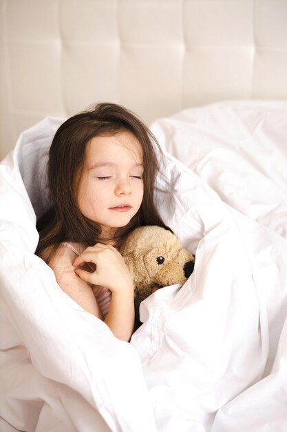 Une jolie petite fille s'est réveillée dans son lit et s'étire et bâille dans la chambre le matin Une nouvelle