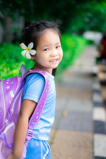 Jolie petite fille avec sac à dos marchant dans le parc prêt pour la rentrée scolaire