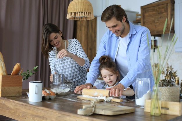 Jolie petite fille et ses parents s'amusent en cuisinant ensemble dans la cuisine à la maison.