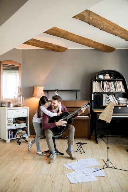 Jolie petite fille et son beau père jouent de la guitare