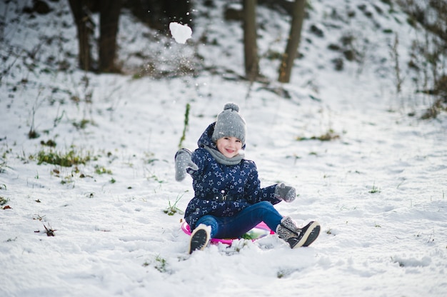 Jolie petite fille avec soucoupe traîneaux à l'extérieur le jour de l'hiver.