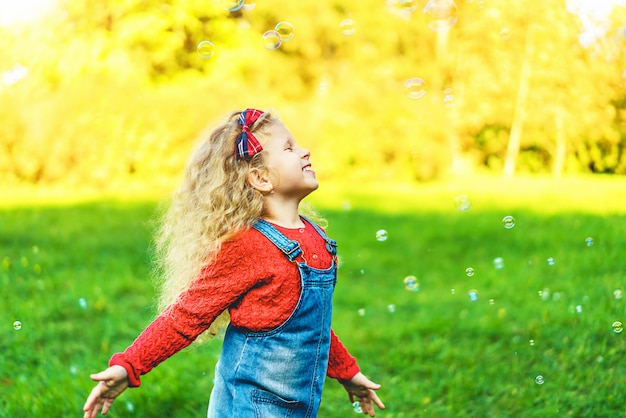 Jolie petite fille soufflant des bulles dans le parc.